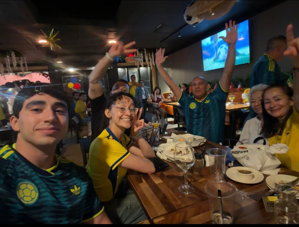 Mateo with family and friends in Colombia jerseys, celebrating at a restaurant during a soccer match